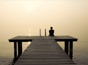 man sits at end of dock as he contemplates finding the best rehab center for alcoholism to address his alcohol abuse issues